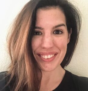 Kelly Riddle with long, light brown hair with side-swept style, smiling at the camera.
