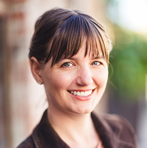 Head shot of Jodi Reeves Eyre. Jodi is a white woman with brown hair. She is smiling.