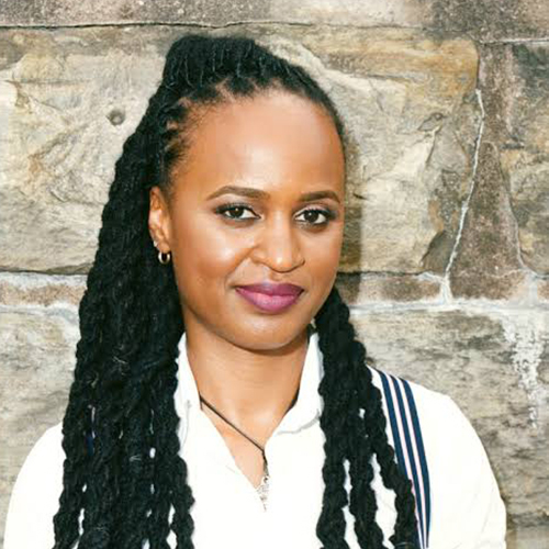 Headshot of Stacey Patton in white button down shirt, standing in front of stone wall.