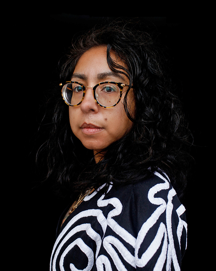 Headshot image of Jennifer Ferretti wearing black and white top against black background.