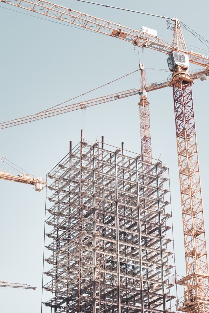 gray metal building frame near tower crane at daytime